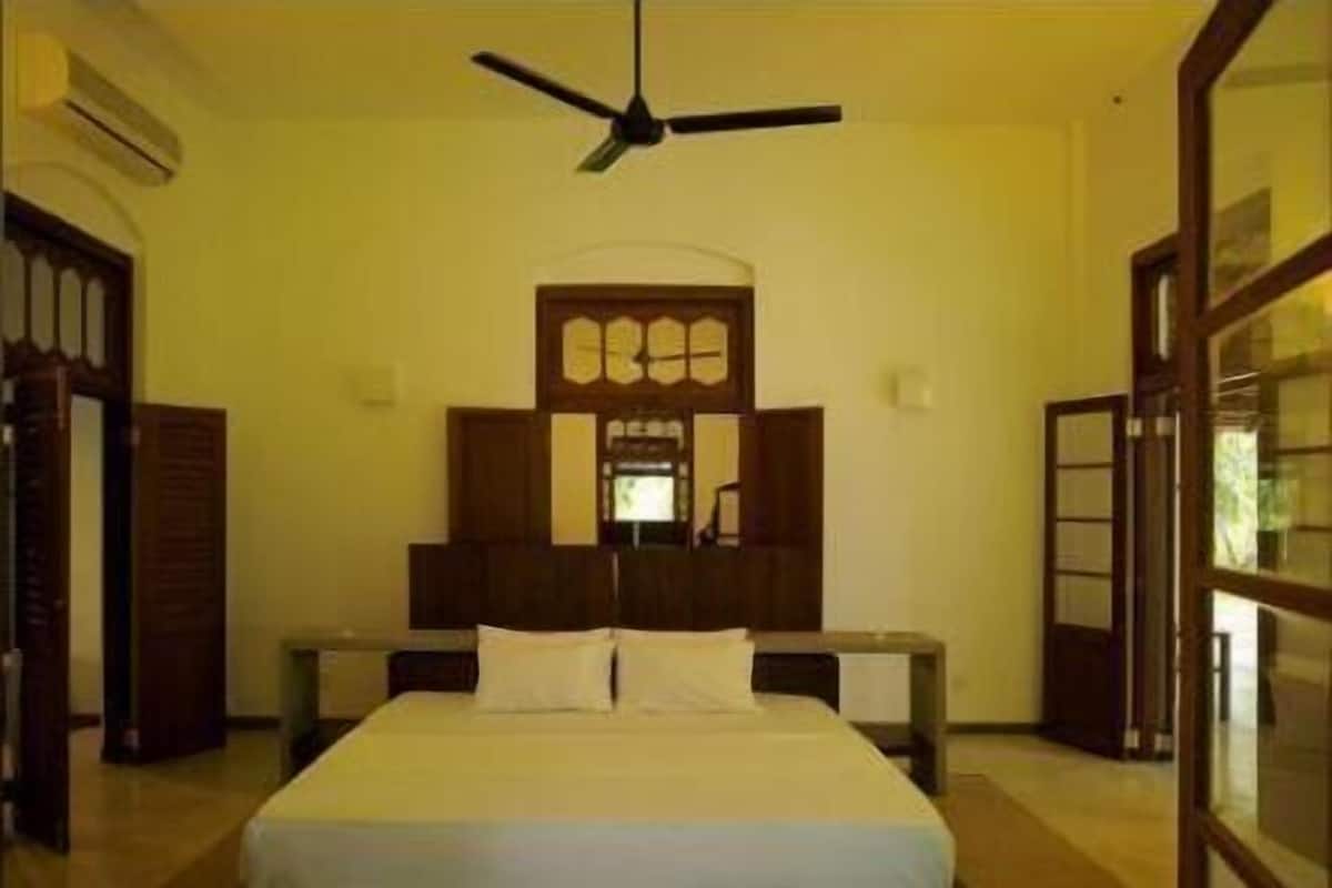 A bedroom with a bed, a ceiling fan, and a wooden headboard.