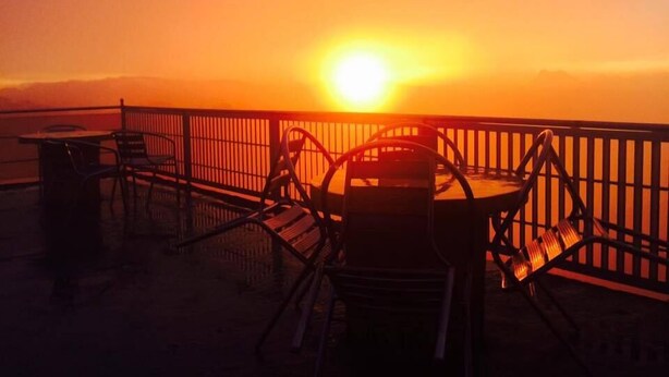 A sunset view from a balcony with chairs and a table. - Pure Nature Hotel (Kandy)