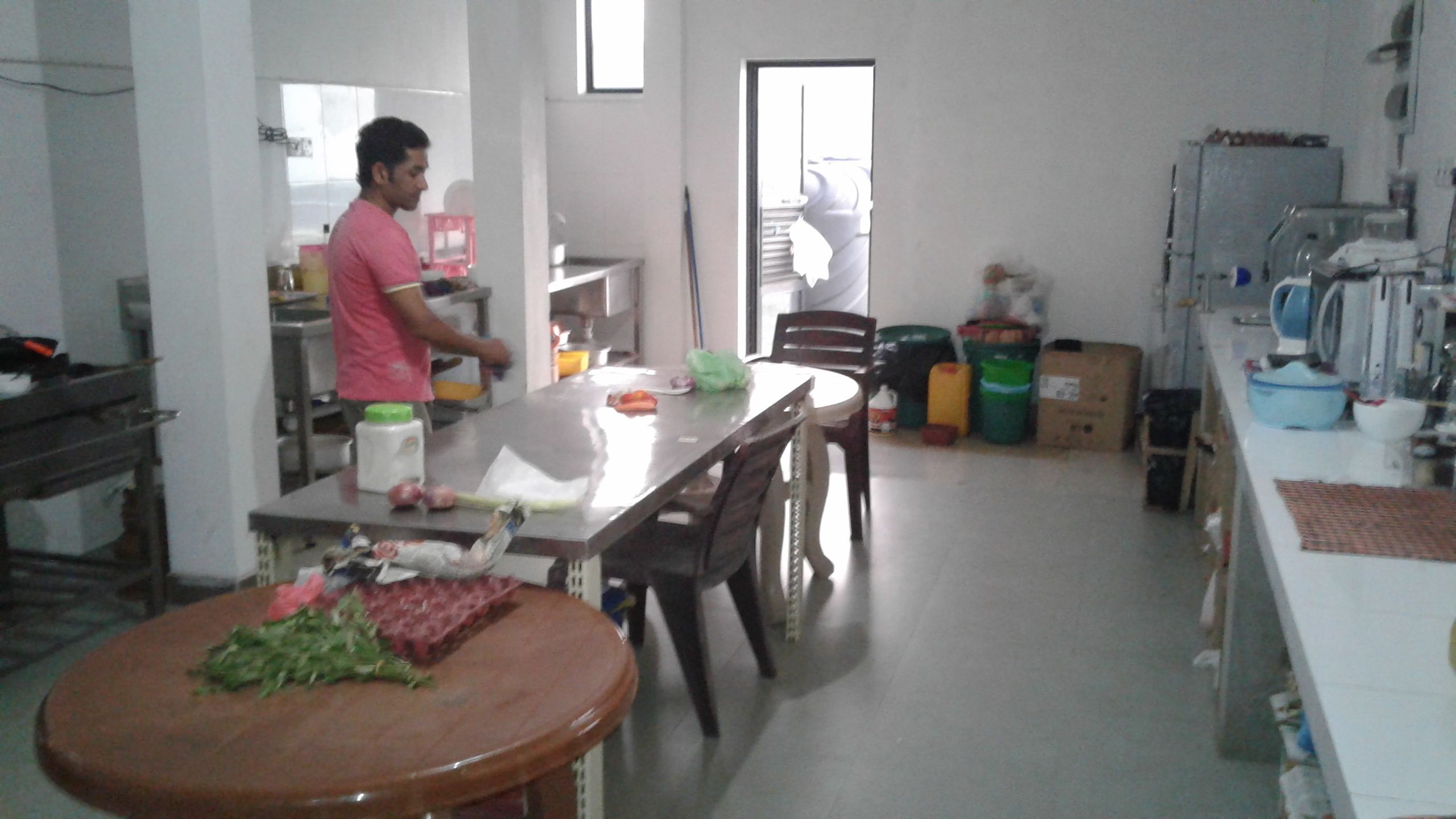 A kitchen with a dining table, chairs, and various kitchen appliances. There are boxes and containers on the floor.