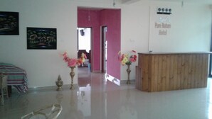 A hotel reception area with a wooden desk, two flower vases, and a sign for the Pure Nature Hotel. - Pure Nature Hotel (Kandy)