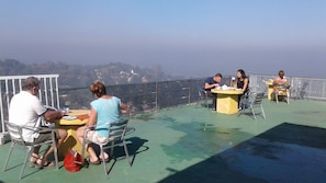A terrace with metal chairs and tables, overlooking a scenic view. - Pure Nature Hotel (Kandy)