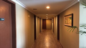Un pasillo con suelo de madera, paredes blancas y una puerta con la inscripción '100'.