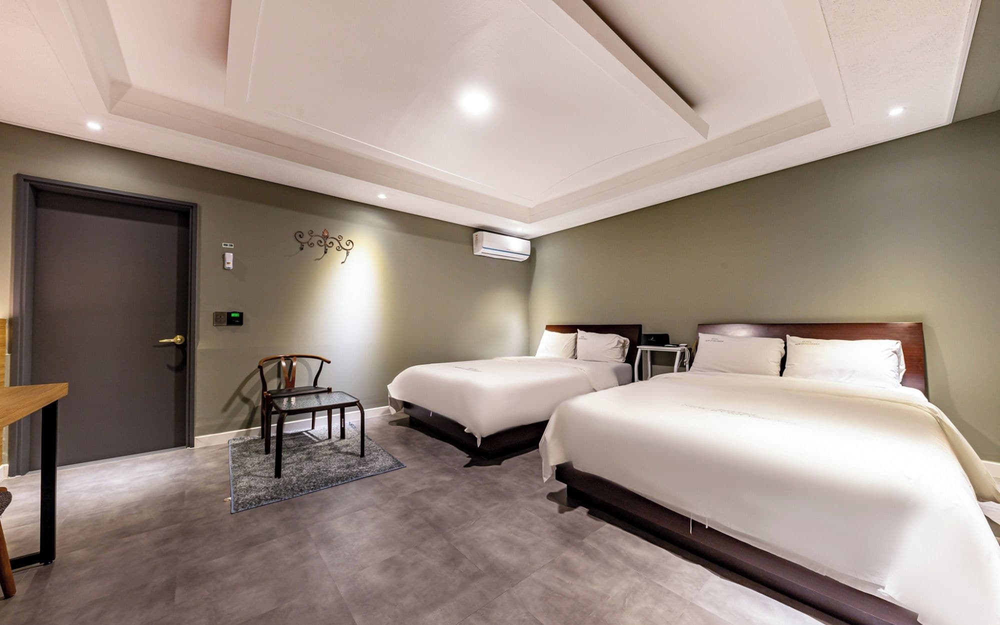 Habitación de hotel con dos camas, un escritorio, una silla y una puerta.