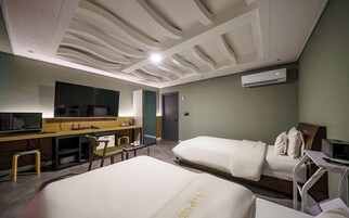 A hotel room with two beds, a desk with a chair, a television, and a large mirror.