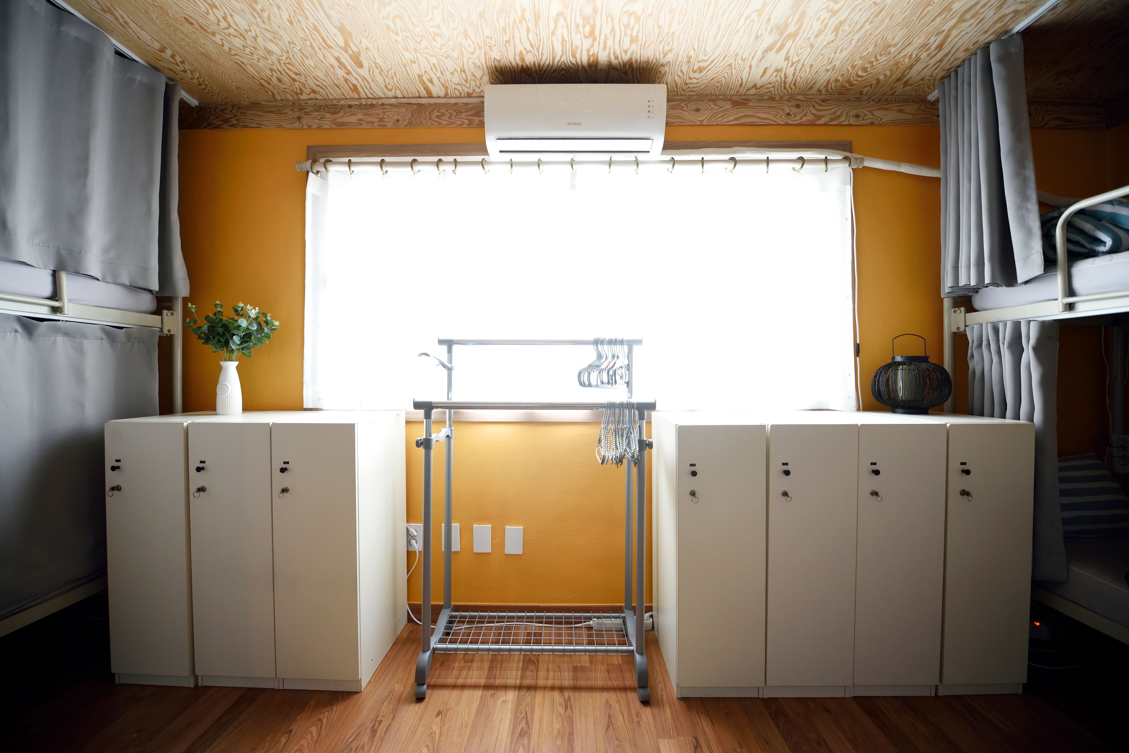 A compact room with a window, a drying rack, and a small kitchenette area.