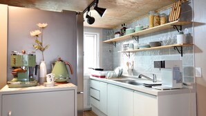 A kitchen with white cabinets, a coffee machine, a kettle, and a sink. - The One Hostel (Seoul)