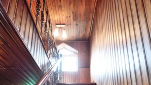 A wooden staircase with a metal handrail and a light fixture at the top. - The One Hostel (Seoul)