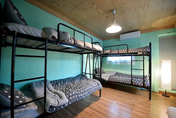 A room with bunk beds, wooden floors, and a ceiling fan.
