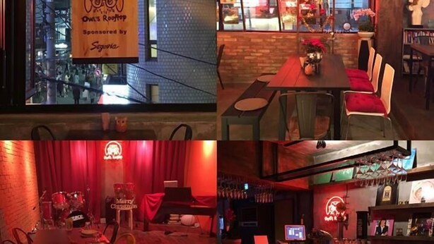 A restaurant interior with a cozy ambiance, featuring a bar area, dining tables, and a stage for live performances. - The One Hostel (Seoul)