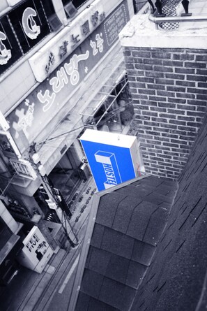 A building with a blue sign indicating a room for rent. - The One Hostel (Seoul)
