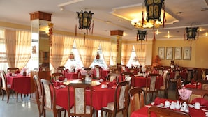 Comedor con varias mesas dispuestas con manteles rojos y sillas de madera.