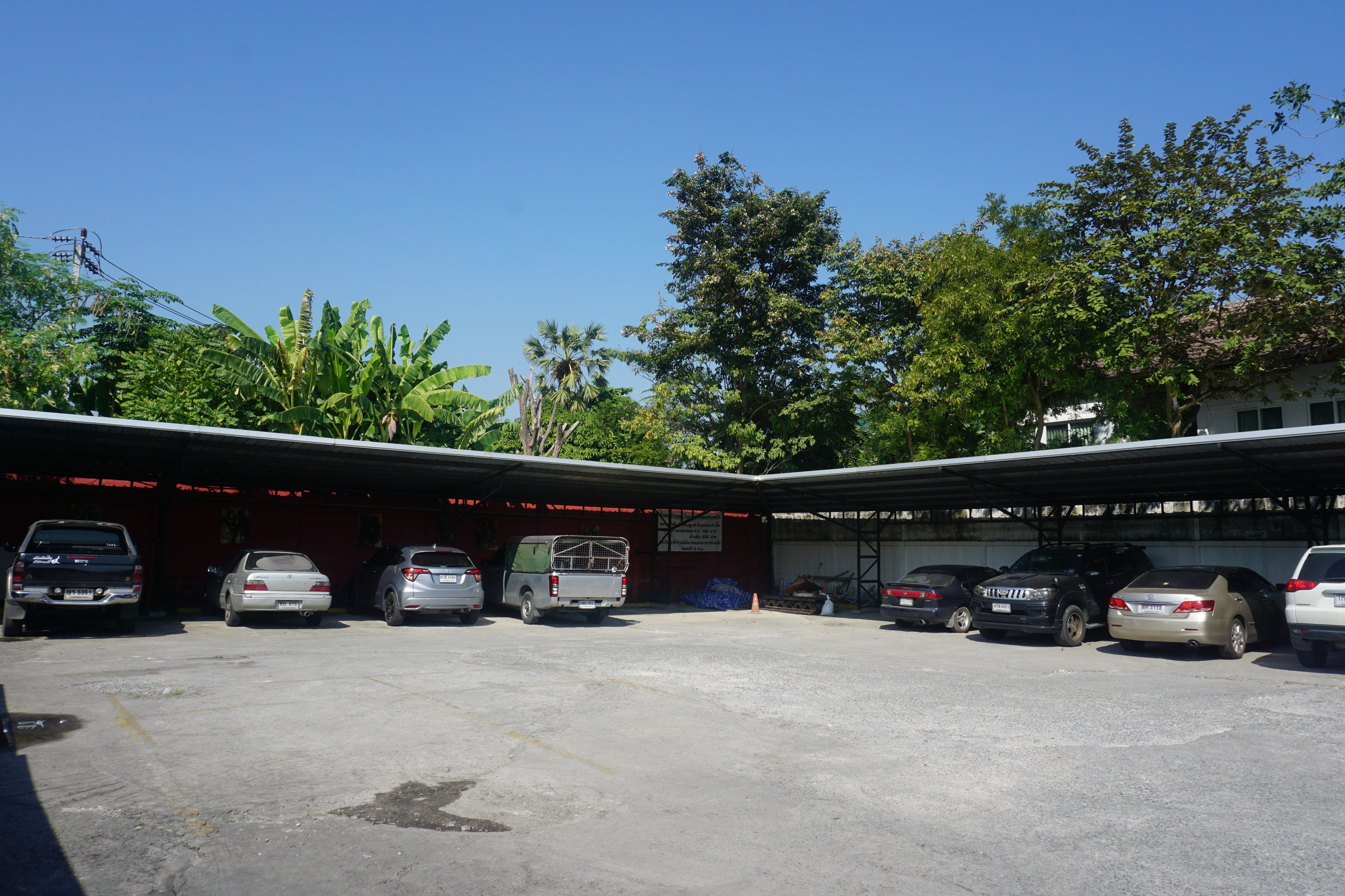 A parking area with several cars and a covered structure.