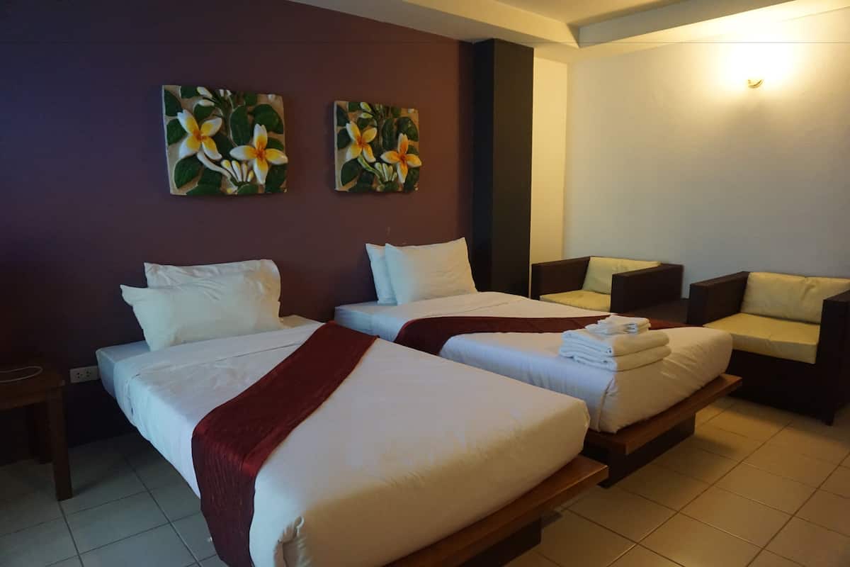 Habitación de hotel con dos camas, un sofá y obras de arte en la pared.