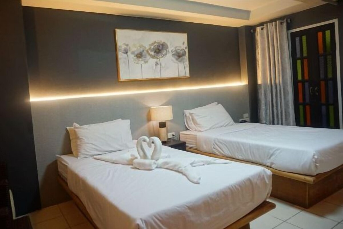 Una habitació d'hotel amb dos llits, una tauleta de nit, una làmpada i un quadre a la paret.