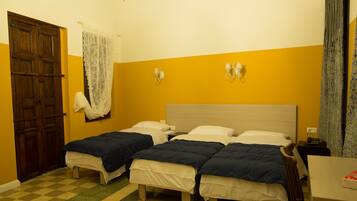 A room with two beds, a wooden door, a checkered floor, and a wall-mounted light fixture.