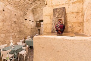 A restaurant with stone walls, checkered tablecloths, and a decorative vase.
