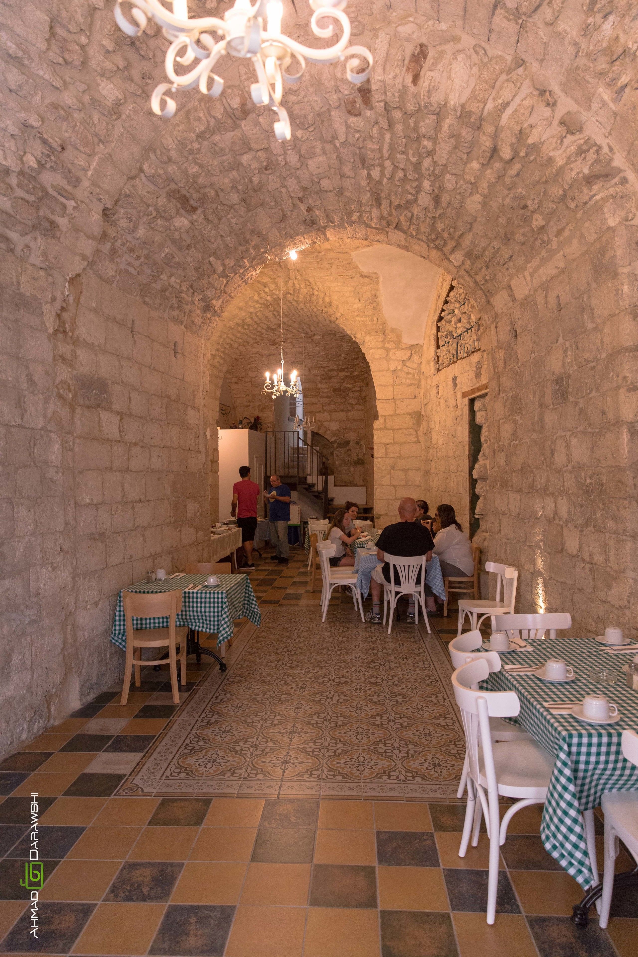 Un intérieur aux murs de pierre, aux nappes à carreaux et agrémenté d’un lustre.