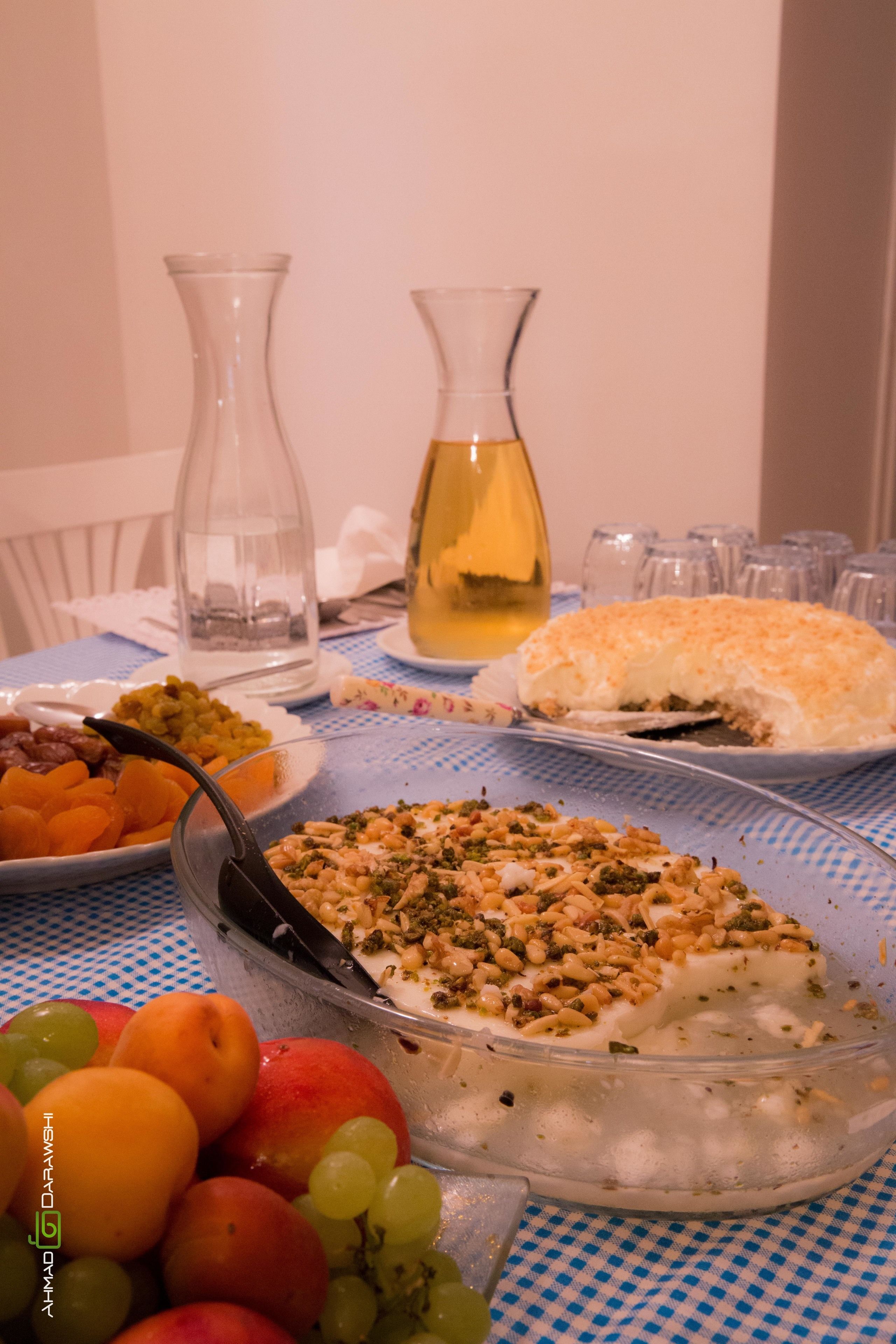 A dining table with various dishes, including a glass bowl of salad, a plate of fruit, and a pitcher of yellow liquid.
