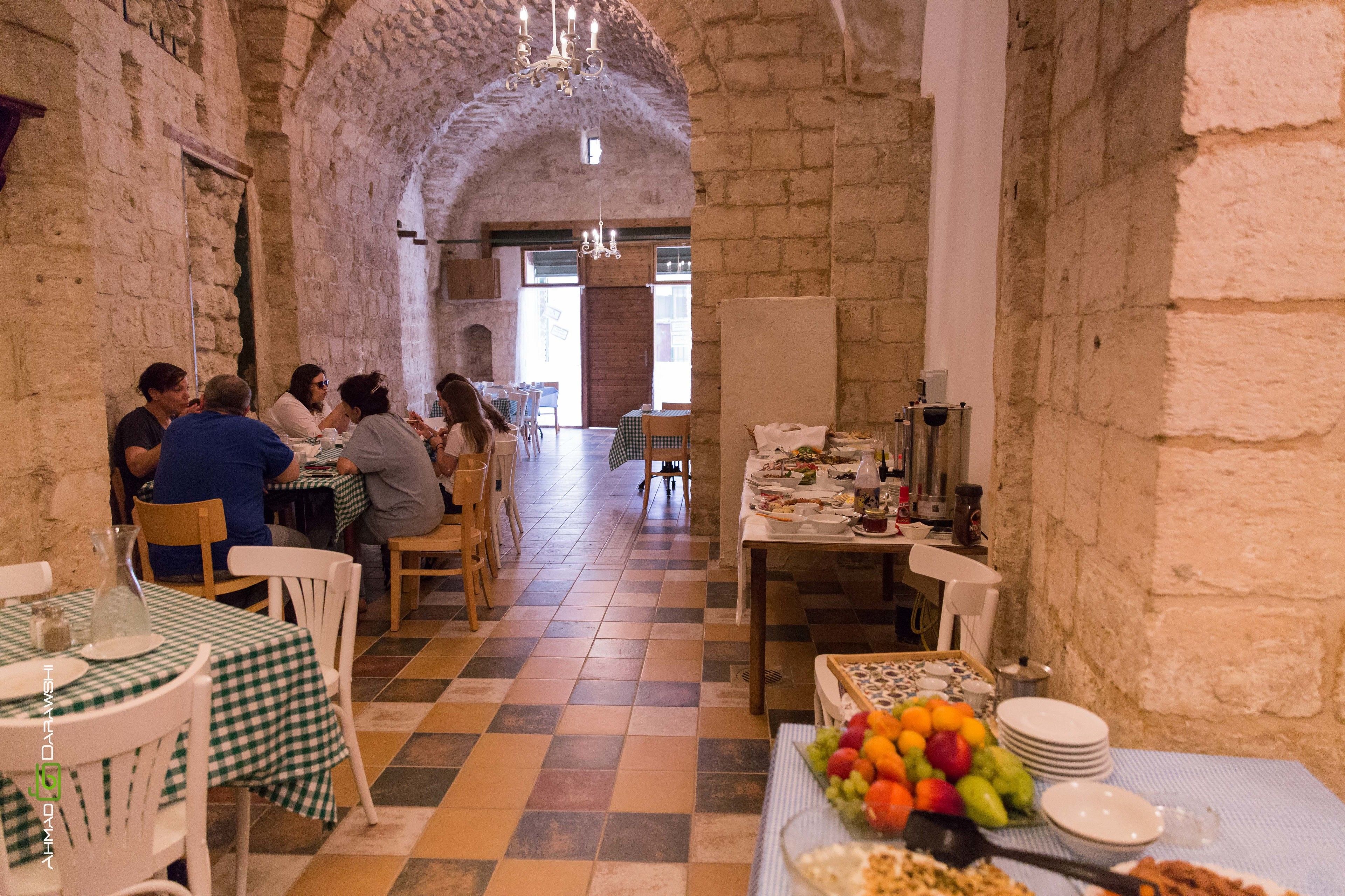 A dining area with stone walls, checkered tablecloths, and a central table with a fruit display.