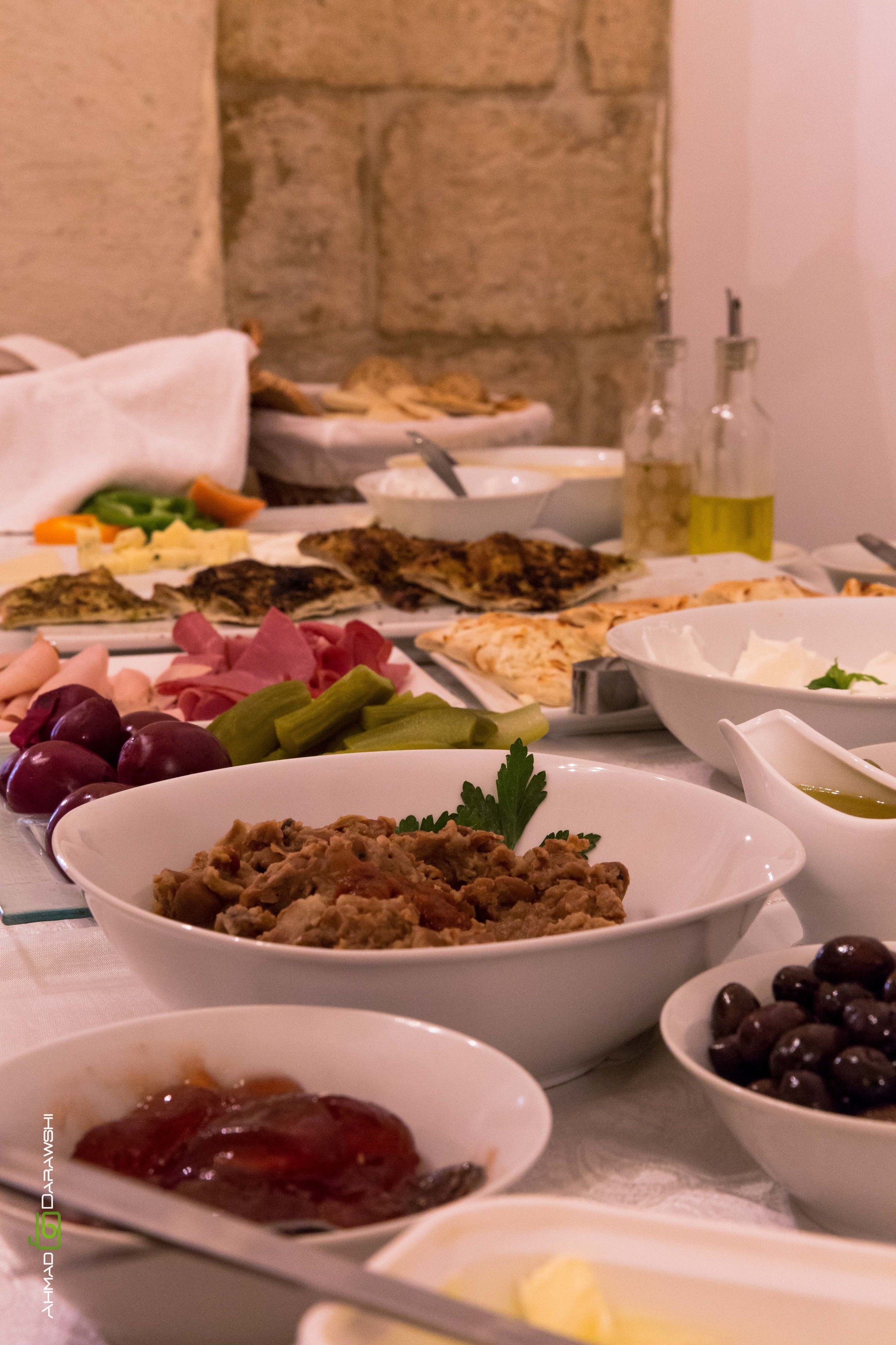 A buffet table with various dishes including meats, cheeses, olives, and pickles.