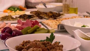 A buffet table with various dishes including meats, cheeses, olives, and pickles.