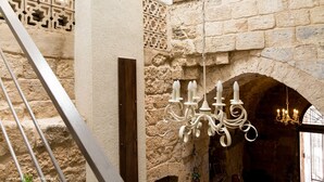 Un intérieur en pierre agrémenté d’un lustre et d’un escalier.