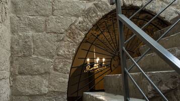 Un escalier en pierre, agrémenté d’une rampe en fer forgé, mène à une porte surmontée d’un candélabre.