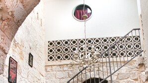 Un escalier en pierre avec une rampe métallique menant au deuxième étage.