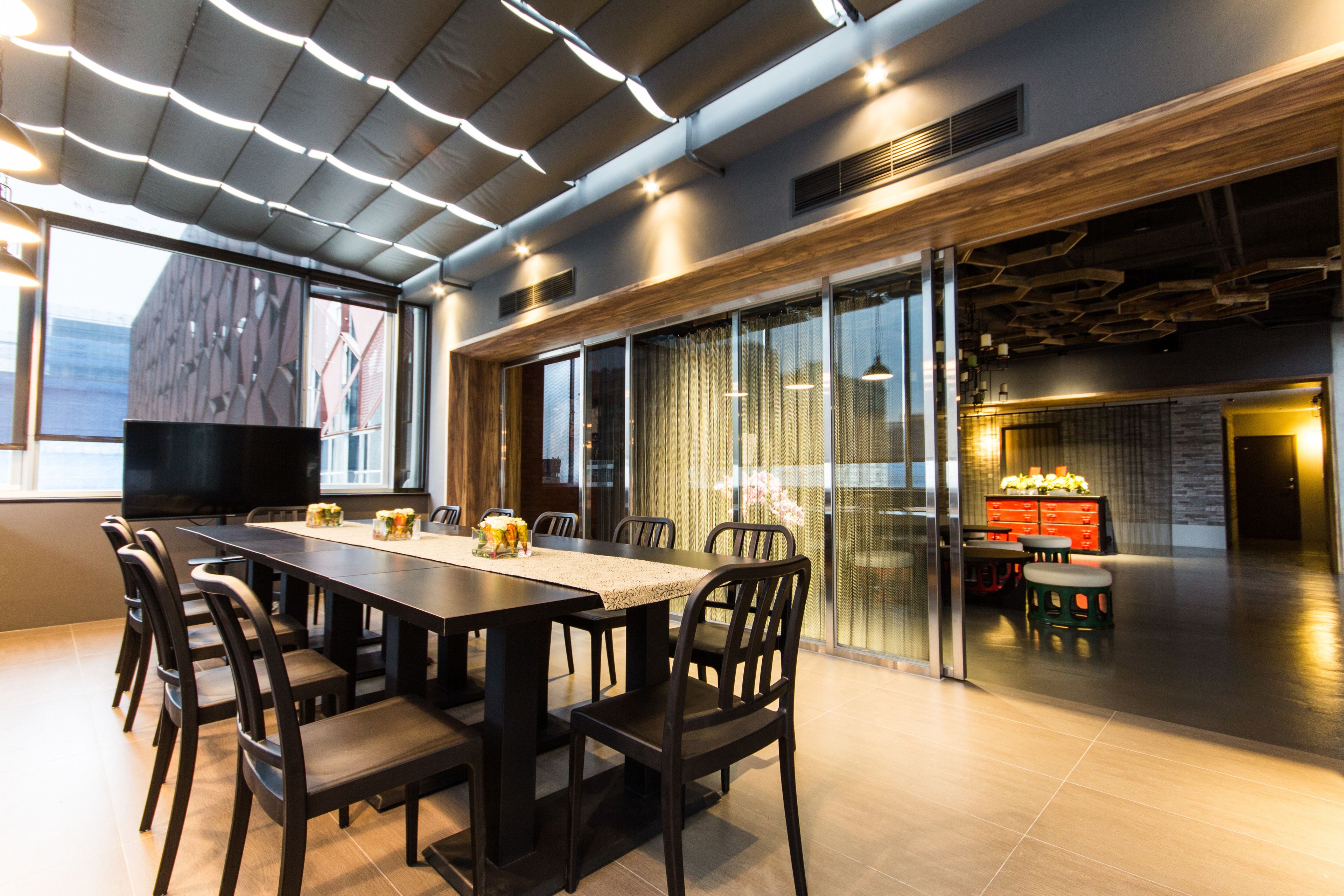 A modern dining area with a long table, chairs, and a television.