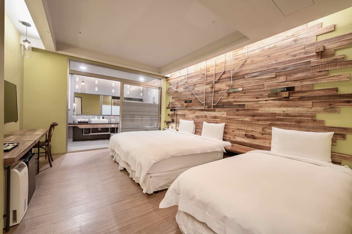 A hotel room with two beds, a wooden accent wall, a kitchenette, and a dining area.