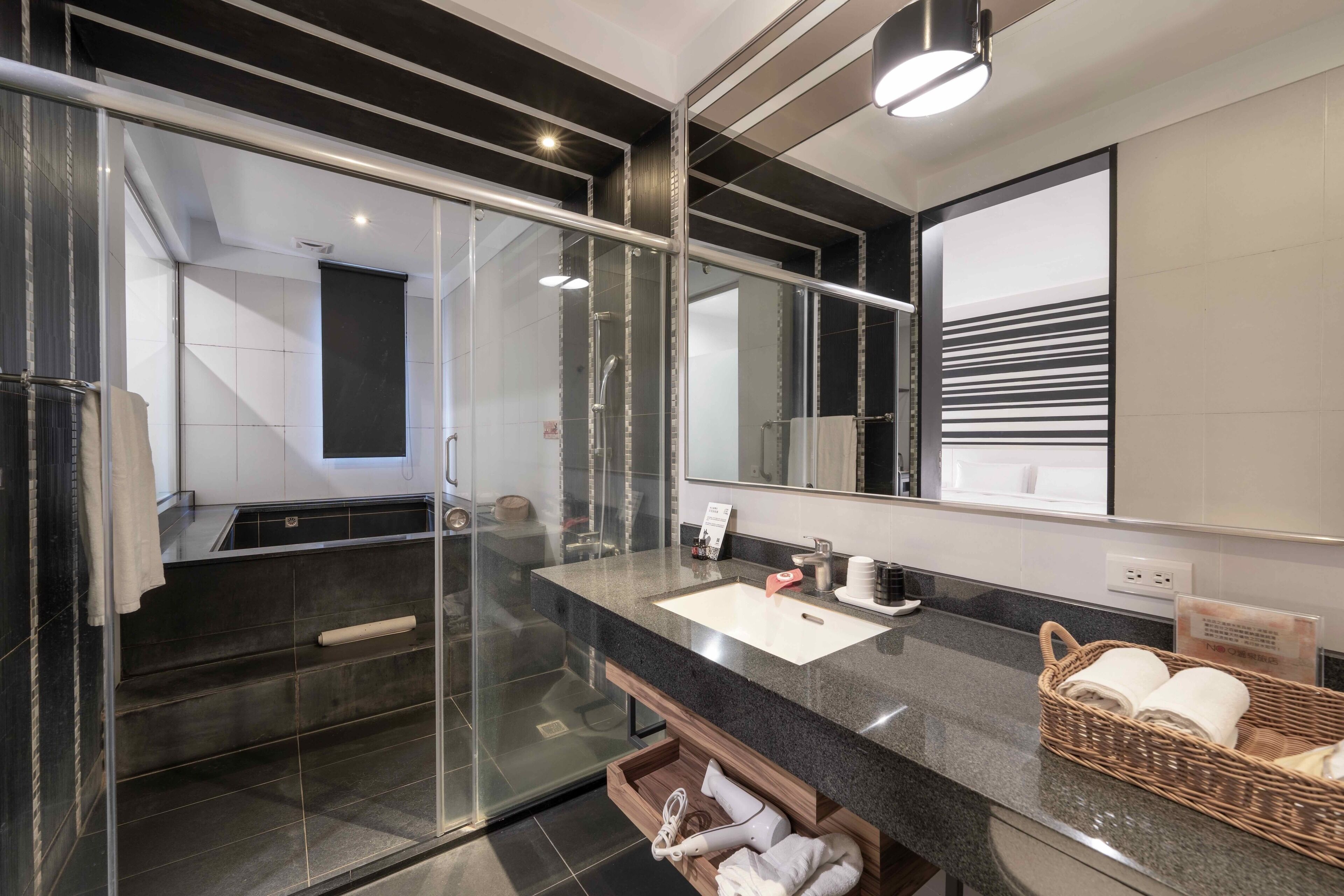 A modern bathroom with a glass shower enclosure, a large mirror, and a granite countertop.