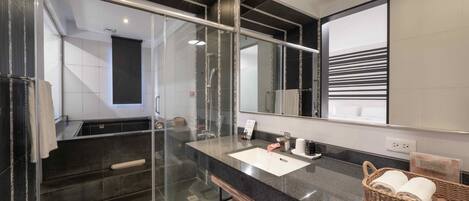 A modern bathroom with a glass shower enclosure, a large mirror, and a granite countertop.