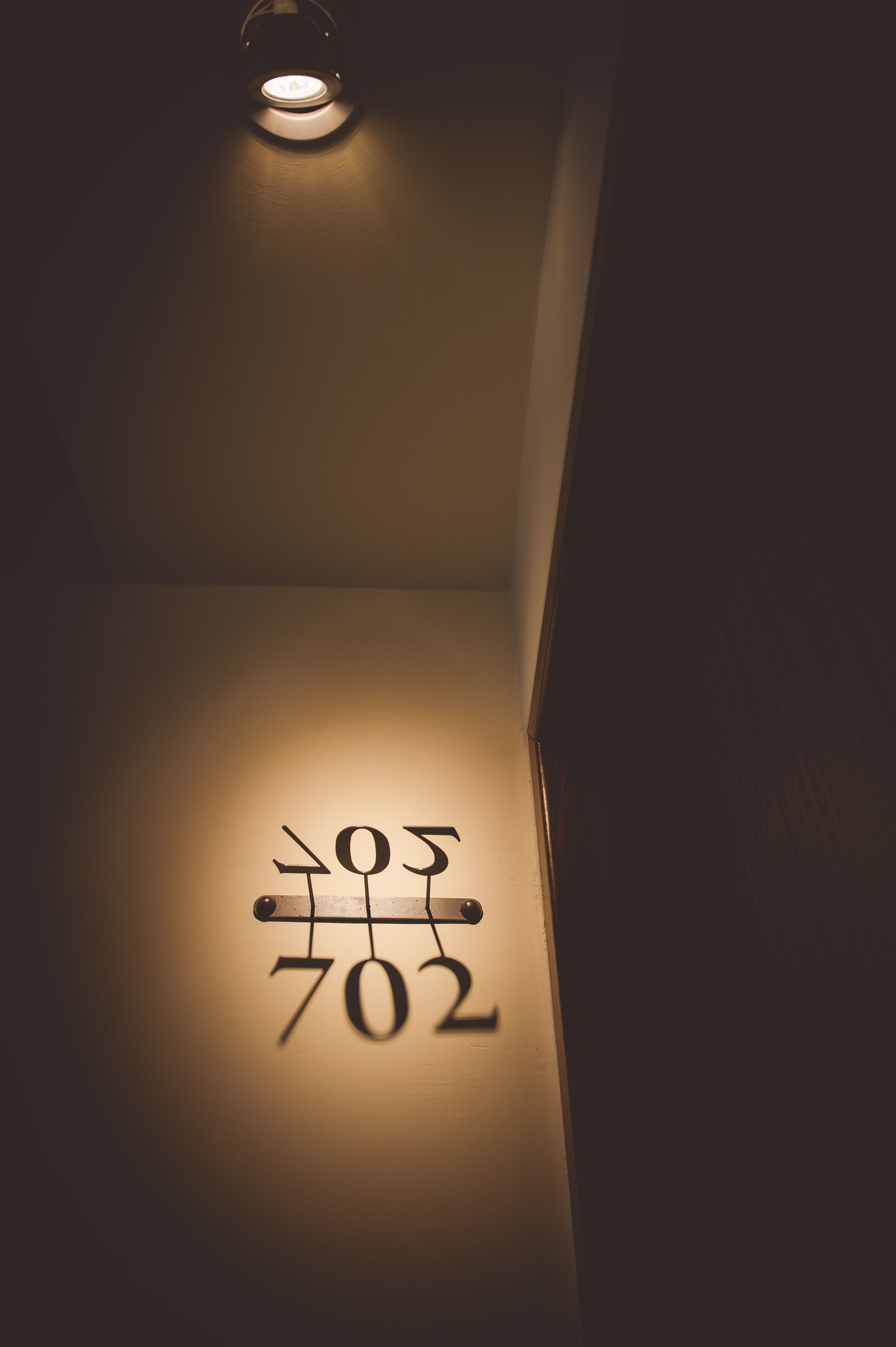 Ein an der Wand befestigtes Schild mit den leuchtenden Nummern „702“ und „505“ in einem schwach beleuchteten Gang.