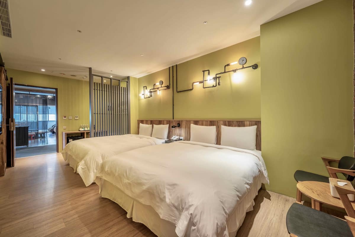 A hotel room with a large bed, a desk with a chair, and a small table with a chair.