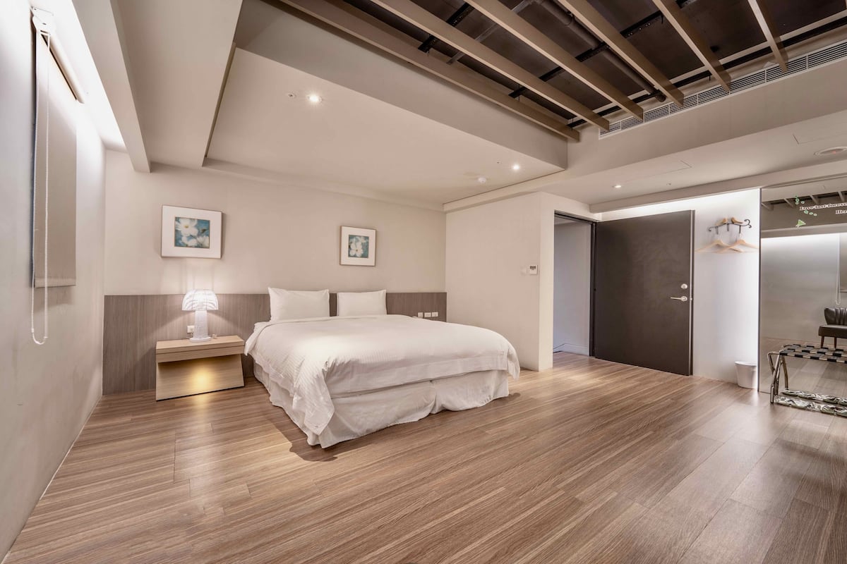 A modern bedroom with a large bed, bedside tables, and a wardrobe.