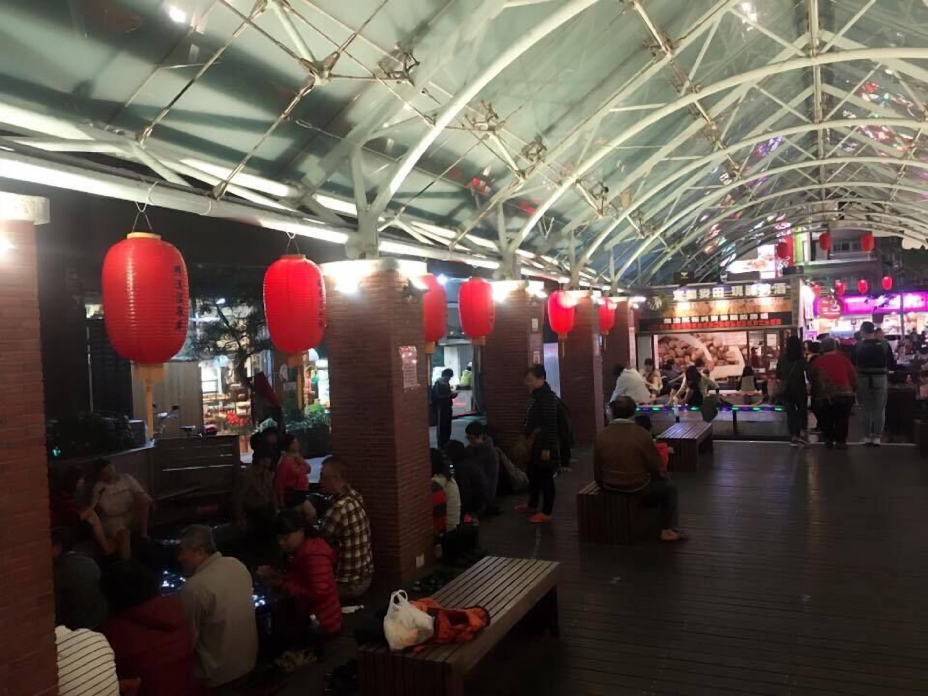 Un mercado interior con un techo alto en arco y faroles rojos.