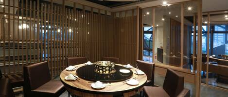 A modern dining area with a round table, chairs, and a central heating element.