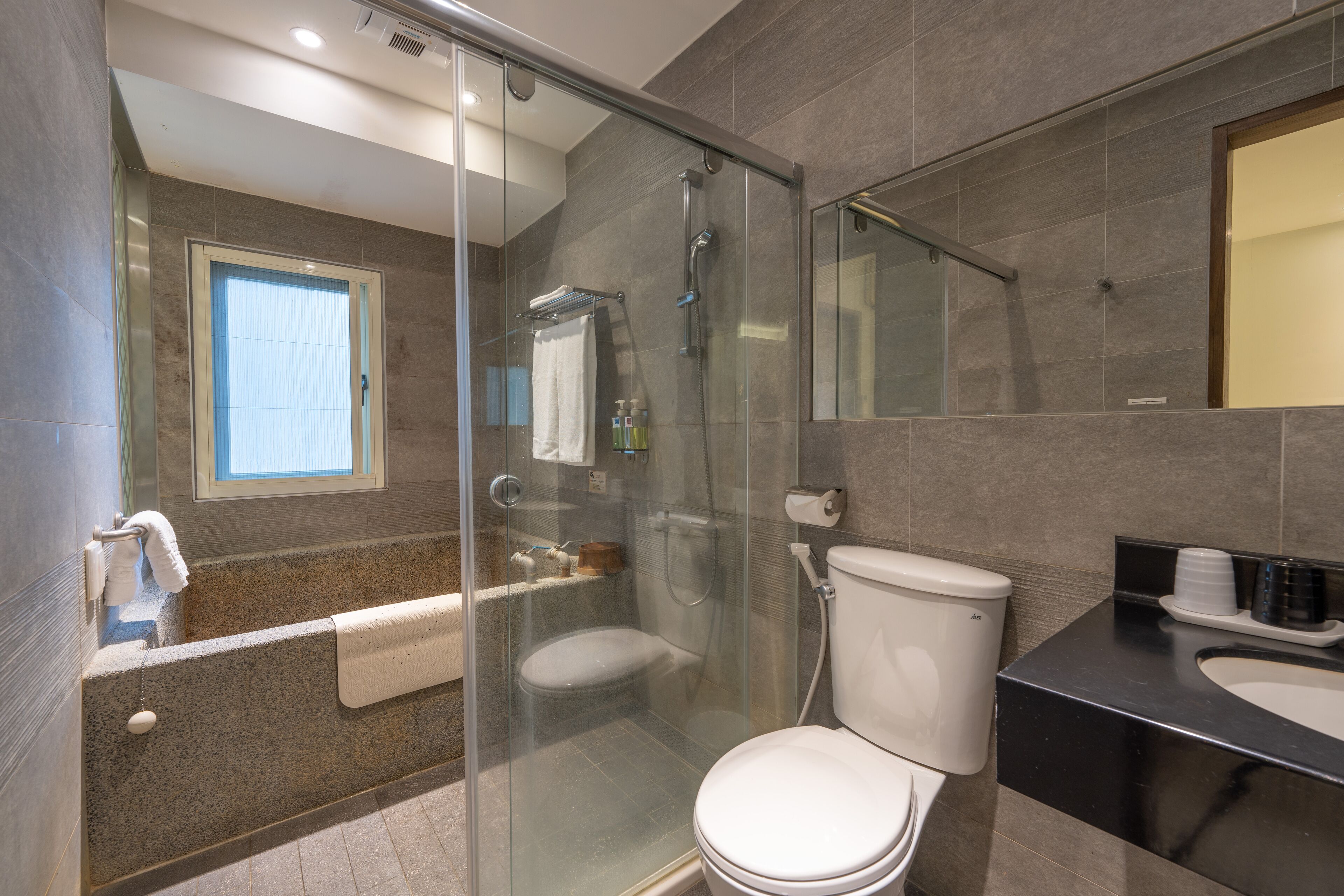 A modern bathroom with a glass-enclosed shower, a bathtub, and a toilet.