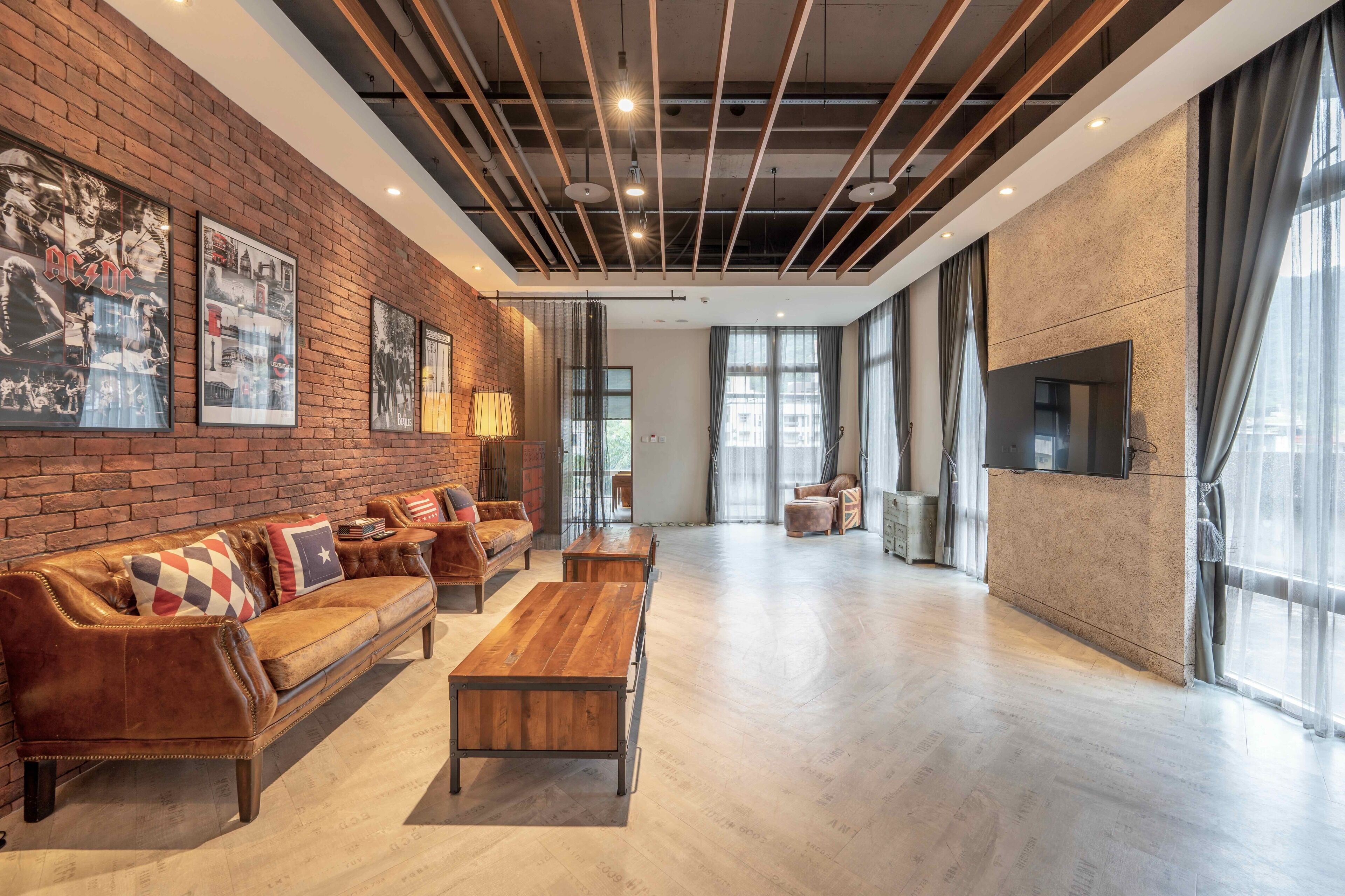 A spacious room with a brick wall, wooden furniture, and large windows.