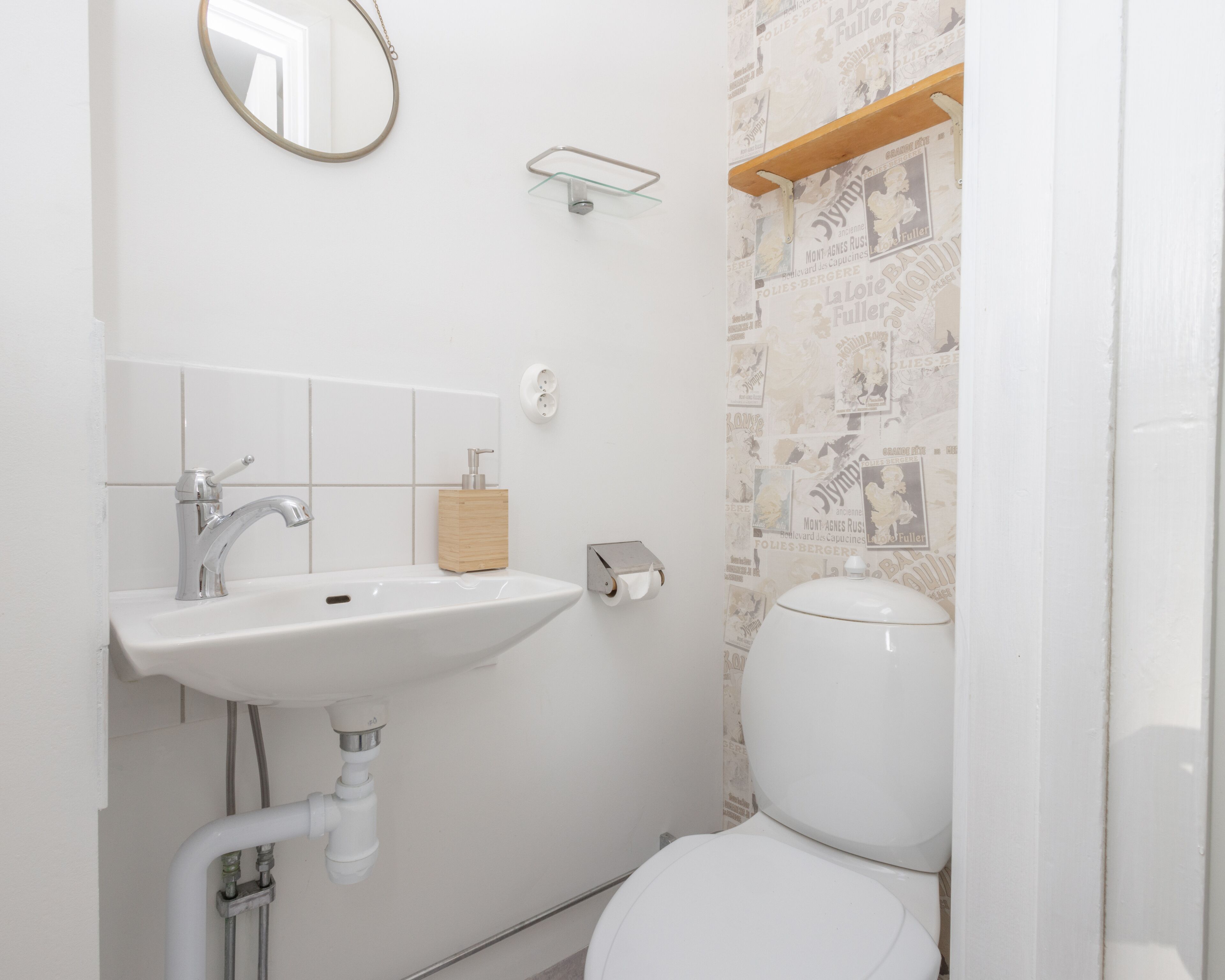 Ein Badezimmer mit weißem Waschbecken, einem Spiegel, einer Toilette und einer Duschkabine.