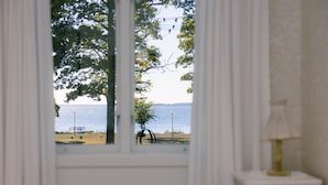 A room with a view of a park and a body of water through a window. - Pensionat Strandhagen (Farjestaden)