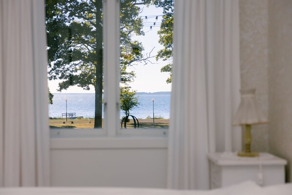 Una habitación con vistas a un parque y un cuerpo de agua a través de una ventana.