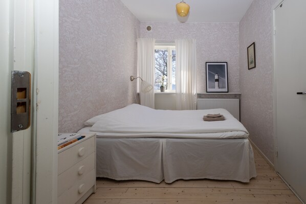 A bedroom with a bed, a dresser, a window with curtains, a radiator, and a framed picture on the wall. - Pensionat Strandhagen (Farjestaden)