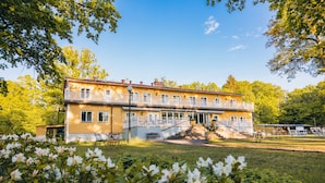 A two-story building with a balcony, a staircase leading to the upper floor, and a front porch with outdoor seating. - Pensionat Strandhagen (Farjestaden)