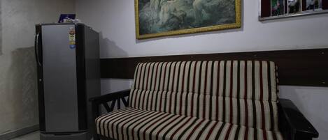 Una habitación con un sofá, un refrigerador y un cuadro en la pared.