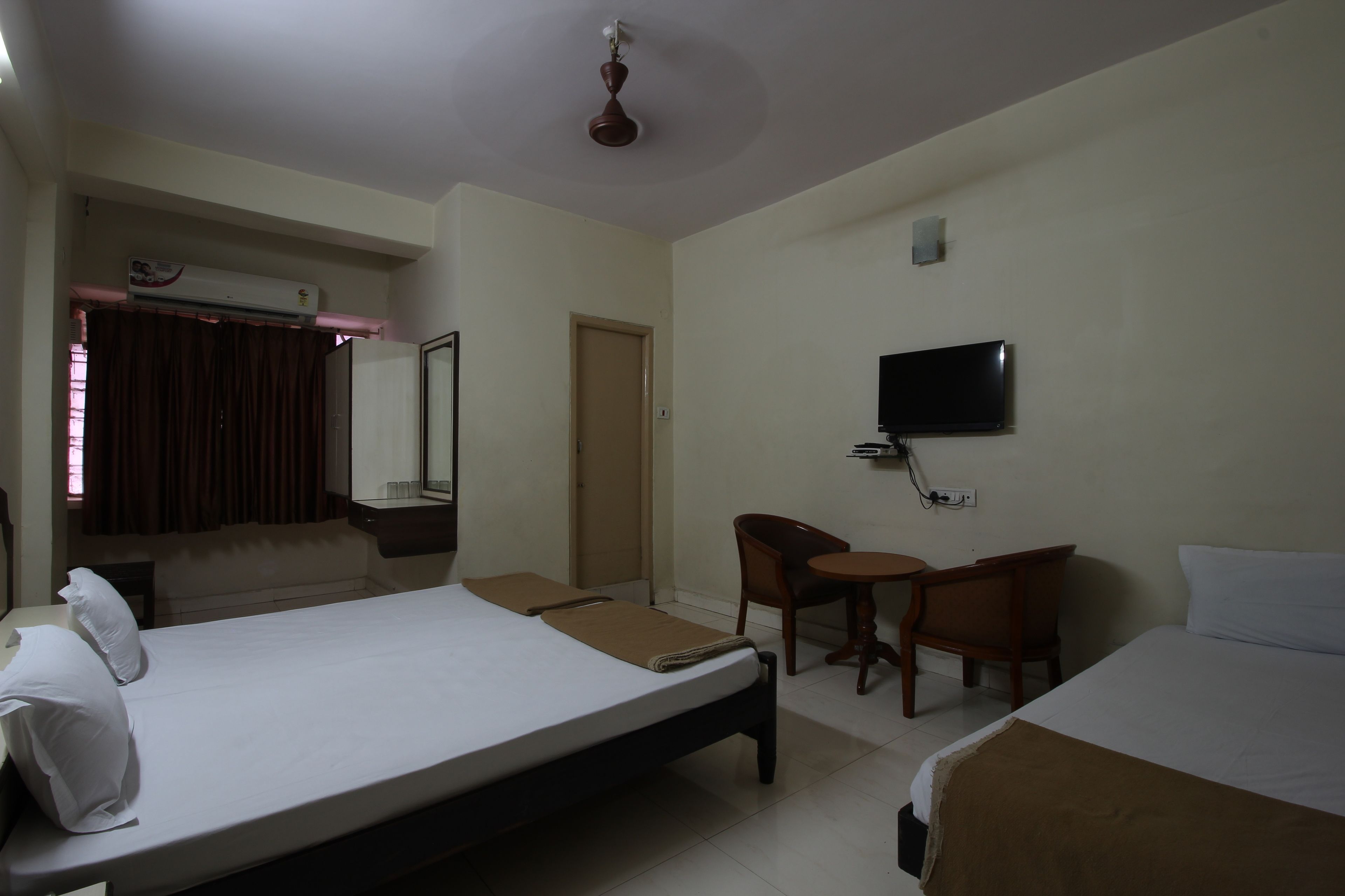 A hotel room with two beds, a TV, a desk, and a chair.