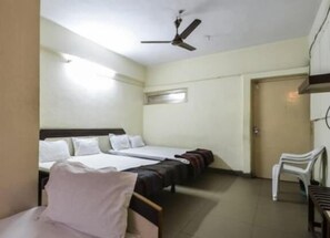 A hotel room with two single beds, a ceiling fan, a small window, and a door.