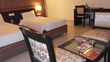 A hotel room with two beds, a desk, a chair, and a coffee table with magazines.