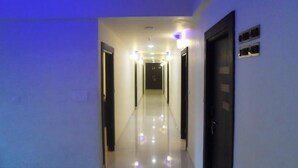 A hotel hallway with a reflective floor, doors on both sides, and overhead lighting. - Hotel Nera Regency (Hyderabad)