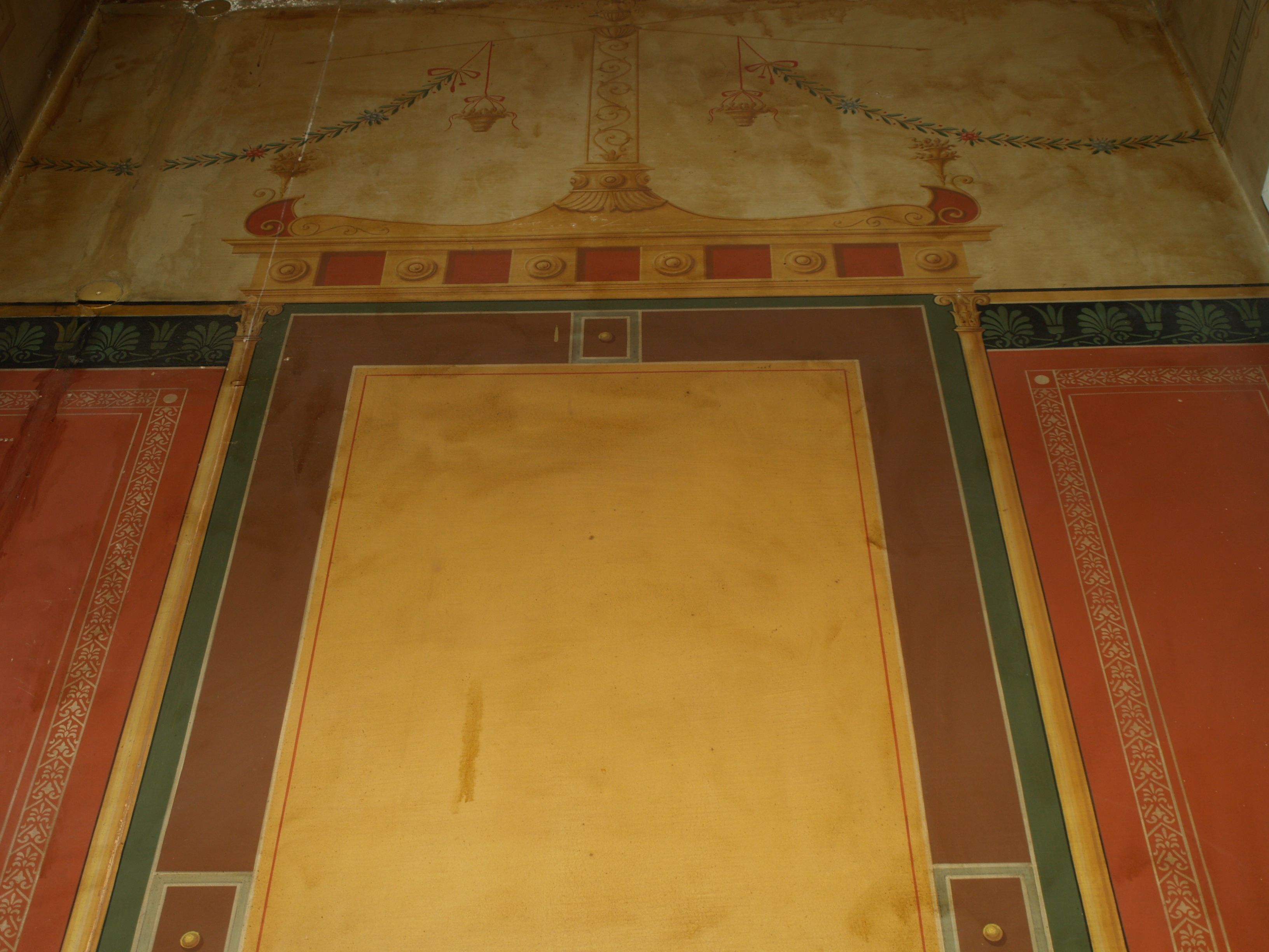 A room with a large central yellow area, possibly a mural or artwork, surrounded by red and green decorative borders.